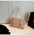 Detail of light pink matelassé tote bag showing vertical quilted texture and gold accents - Pink
