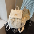 Mochila de lona crema con bordado amarillo y múltiples bolsillos en un estudio - Blanco Roto