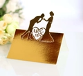 Detail of laser-cut gold wedding place card with Mr & Mrs text and romantic couple silhouette - Reflective Gold
