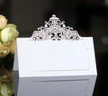 White laser cut lace wedding place cards with hollow flower design on black surface - White