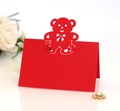 Laser-cut red teddy bear silhouette place card on white glossy surface with white roses - Pearlescent Red