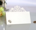 Macro detail of white lace crown place card with laser-cut hollow pattern and gold emblem - Ivory