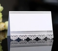 Macro shot of white laser-cut lace place card with pearlescent finish on black mirror - White