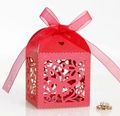 Macro shot of red laser-cut wedding favor box with floral patterns and a silk ribbon bow - Pearlescent Red