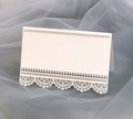 Close-up of white laser-cut lace wedding place card on blue tulle background - Ivory