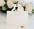 Detail view of laser cut boy and girl silhouette on white paper wedding place cards - Ivory