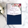 Dettaglio dell'invito di nozze blu navy con carta floreale acquerello su sfondo marmo - Blu magico