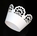 Macro shot of laser-cut white lace cupcake wrapper with intricate crown pattern - White