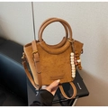 Detail der braunen Wildleder-Beuteltasche mit Leder-Spleißen, Griff und Perlen-Anhänger - Braun