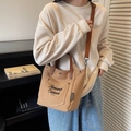 Bolso tote de lona marrón y caqui con asas de cuero mostrado en una modelo real - Marrón