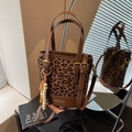Leopard print bucket bag with dual handles and beaded charm on a mirrored surface - Brown with Pendant