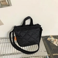 Borsa a secchiello trapuntata nera con tracolla e dettaglio etichetta arancione - Nero
