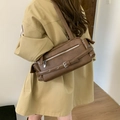 Retro dunkelbraune rechteckige Schultertasche mit Schnallen auf dem Rücken getragen - Braun