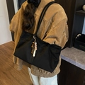 Black large capacity tote bag with wooden bead charm worn by a model in interior setting - With Charm / Black