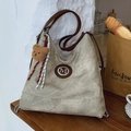 Bolso tote grande retro verde musgo con logotipo M y colgante de oso en una mesa de madera - Gris Con Colgante