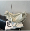 Detail of cream nylon dumpling bag featuring side drawstring and adjustable strap - White