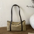 Detail of olive green suede shoulder bag on a vintage wood table with minimal decor - Khaki