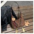 Dettaglio borsa hobo leopardata con tracolla in pelle e ciondolo a forma di orso su panca - Stampa leopardata