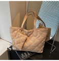 Dettaglio della borsa tote trapuntata beige con ricami floreali e ciondolo - Cachi