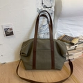 Détail du sac fourre-tout en toile olive avec poignées en cuir marron et bandoulière - Vert