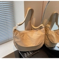 Beige nylon crossbody dumpling bag with adjustable strap shown by a window side mirror - Khaki