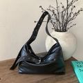 Dettaglio borsa hobo vintage in pelle nera con fibbie argentate su tavolo in legno - Nero