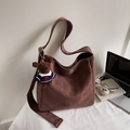 Sac hobo en daim marron avec charm ours en peluche sur un bureau blanc épuré - Café Daim Avec Charme