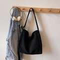 Sac seau noir mat minimaliste avec bandoulière réglable sur un cintre en bois - Noir Daim (Sans Charme)