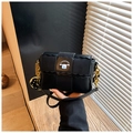Detail der schwarzen matten Leder-Kissentasche mit Goldkette und Cartoon-Hundepatch - Schwarz