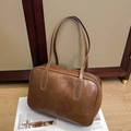 Detail view of caramel brown vintage leather tote with metal zippers on a magazine - Brown