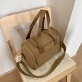 Dettaglio borsa da viaggio kaki con manici rinforzati e tracolla su una sedia in legno - Cachi