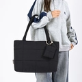 Dettaglio della borsa shopper trapuntata nera con mini pochette su una felpa grigia - Nero