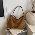 Große braune Hobo-Tasche aus Wildleder mit Lederriemen auf einem Koffer in Freizeitoptik - Braun