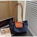 Close-up of navy nylon tote bag showing brown leather flap and golden metal button snap - Blue