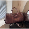 Macro shot of dark brown woven leather travel bag with adjustable strap and handles - Coffee