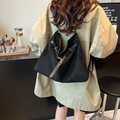 Chic black slouchy tote bag with gold hardware shown on model in a cozy cafe setting - Black