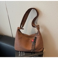 Detailed view of dark brown quilted hobo bag with fringe tassel on art book display - Coffee