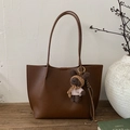 Detail of dark brown tote bag with lychee texture and cute knitted bear charm accessory - Brown with Pendant