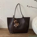 Detail of dark brown tote bag with bear charm on a textured background - Coffee with Pendant