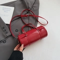 Glossy red cylinder boston bag with top handles and adjustable strap in a stylish scene - Glossy Red