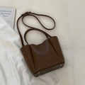 Detail view of the deep brown leather bucket bag bottom with protective metal studs - No Pendant / Brown
