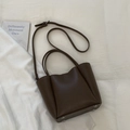 Detail view of the deep brown lychee texture PU leather bucket bag with silver metal feet - No Pendant / Brown