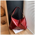 Primer plano de cuero rojo brillante y logotipo metálico en bolso tote amplio - Burdeos