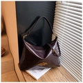 Detalle de bolso hobo de cuero burdeos con logo metálico sobre fondo de madera rústica - Marrón