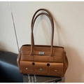 Vista detallada del bolso tote vintage de cuero marrón con bolsillos de cierre giratorio - Marrón