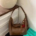 Detail of vintage brown hobo bag with colorful pompom charm on a minimalist wooden background - Brown