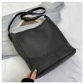 Vue détaillée du sac seau en cuir noir grainé posé sur une veste en jean délavée - Grand / Noir Grand