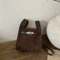 Macro detail of dark brown faux suede texture and silver twist lock on the bucket bag - Brown