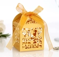 Macro shot of gold laser-cut hollow candy box with floral lace patterns and ribbon - Gold