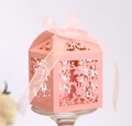 Close-up of pink laser-cut wedding candy box with vine patterns and ribbon bow - Pink